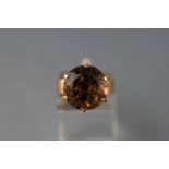 A yellow metal dress ring set with a large round faceted cut smoky quartz. Tests indicate 9ct gold.