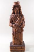 A 20th century carved wood figure of a man wearing a crown and holding a child,