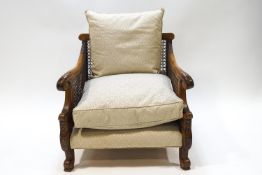 A carved hardwood Bergere armchair with acanthus motif arms raised on scrolled legs 75 cms