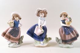 Three Lladro porcelain figures of girls carrying flowers.