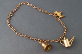 A hallmarked 9ct gold trace link bracelet with three assorted attached charms. Bolt ring clasp.