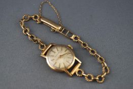 A yellow gold wristwatch by Garrard. Mechanical movement with silver baton dial.
