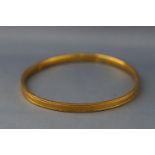 A yellow metal very large bangle with Greek Key design. Marks illegible but tests indicate 9ct gold.