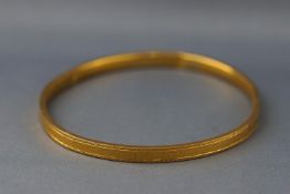 A yellow metal very large bangle with Greek Key design. Marks illegible but tests indicate 9ct gold.