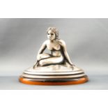 An Italian white metal desk weight, modelled as a seated naked lady, on a faux tortoiseshell base,