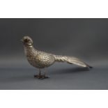 A white metal figure of a pheasant, with red glass eyes.
