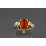 A yellow and white metal single stone ring set with a cushion cut faceted fire opal.