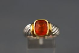 A yellow and white metal single stone ring set with a cushion cut faceted fire opal.
