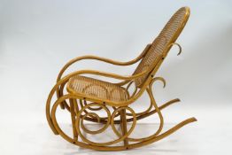 A 20th century bentwood rocking chair with caned back and seat