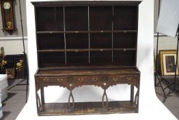 An 19th century and later oak dresser with shaped cornice over two shelves with stags head hooks,