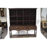 An 19th century and later oak dresser with shaped cornice over two shelves with stags head hooks,