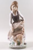 A Lladro porcelain figure of a girl with a cat at her feet.