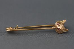 A yellow metal safety pin with fox head design having ruby set eyes.