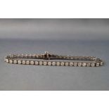 A white metal diamond line bracelet set with fifty round brilliant cut diamonds.