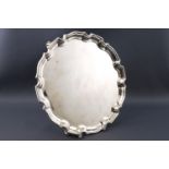A small silver salver with gadrooned edge, raised on three scrolled bracket feet,