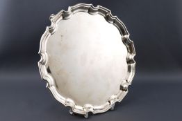 A small silver salver with gadrooned edge, raised on three scrolled bracket feet,