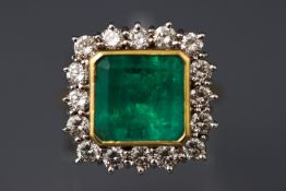 A yellow metal cluster ring set with a square step cut emerald.