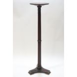 A mahogany torchere with reeded pedestal on triform base,