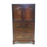 A reproduction mahogany press cupboard on three drawers, the upper half with panelled doors,