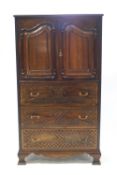 A reproduction mahogany press cupboard on three drawers, the upper half with panelled doors,