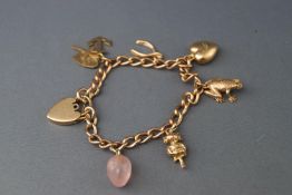 A hallmarked 9ct gold curb bracelet with assorted 9ct gold charms. Padlock and safety chain.