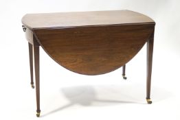 A 19th century oval Pembroke table on square tapering legs with boxwood stringing and brass casters,