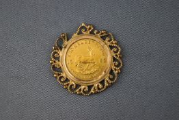 A 1/10 Krugerand within a yellow gold scroll mount.