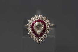 A white metal pear shaped diamond and ruby cluster ring.