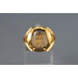 A yellow metal single stone ring set with an oval faceted cut pale smoky quartz. Stamped 18K.