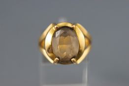 A yellow metal single stone ring set with an oval faceted cut pale smoky quartz. Stamped 18K.