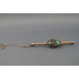A yellow metal bar brooch with central wire wrapped freeform turquoise.