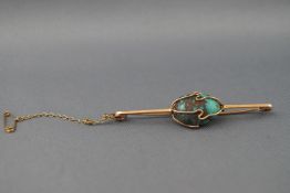 A yellow metal bar brooch with central wire wrapped freeform turquoise.