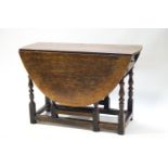 An elm gate leg table on turned balusters with frieze drawer,