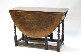An elm gate leg table on turned balusters with frieze drawer,