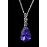 A white metal drop pendant set with a pear faceted cut tanzanite.