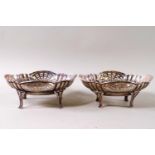A pair of shaped oval silver dishes with pierced decoration, raised on four legs, London 1925,