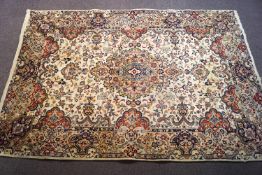 A Kerman Iranian handmade rug with flowers on a cream field within one wide border,