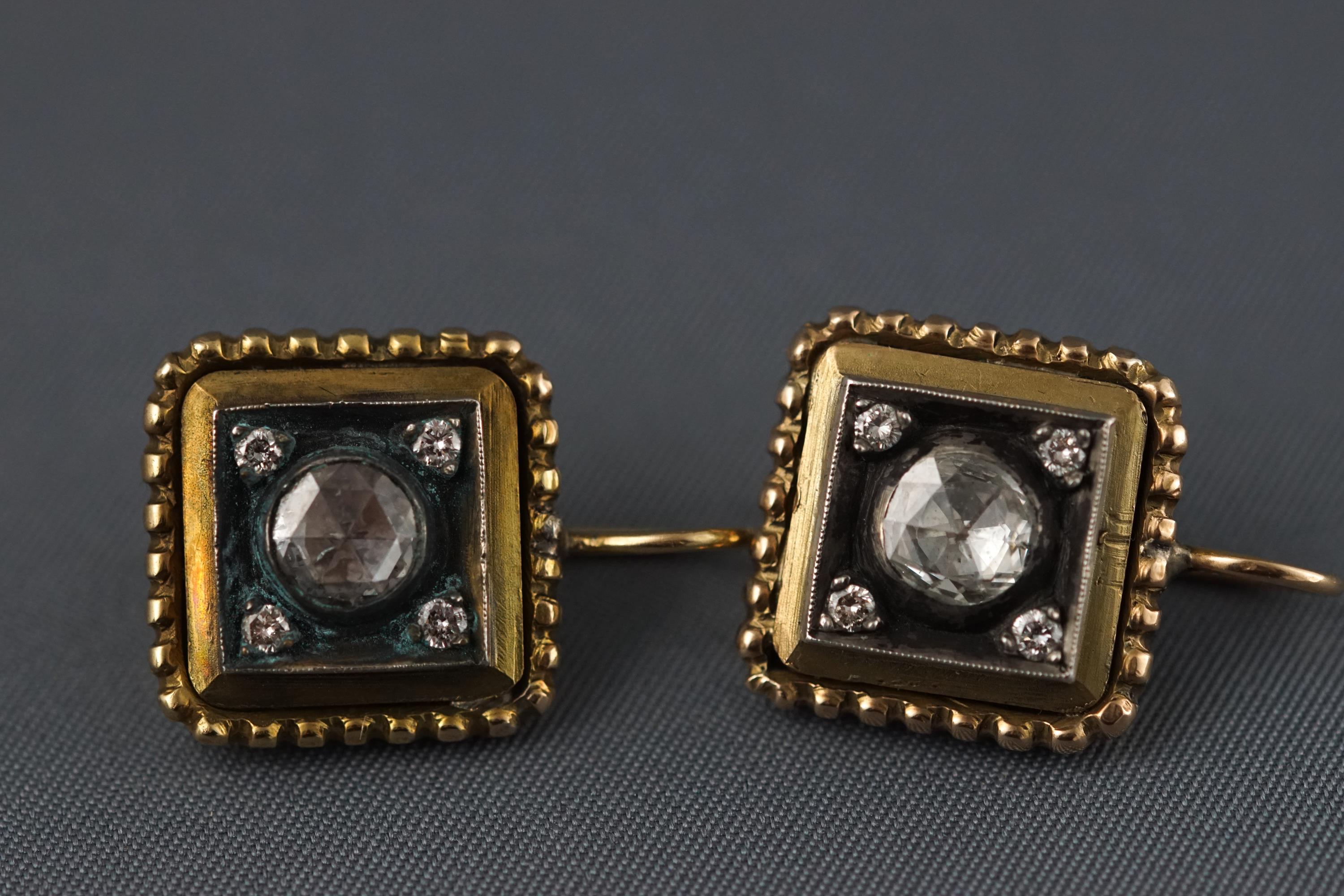 A yellow metal pair of earrings each set with a central rose cut diamond measuring 5.