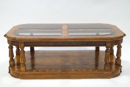 A glass topped walnut veneered coffee table, with eight legs,