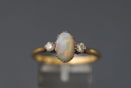 A yellow and white metal three stone ring set with an oval cabochon cut opal.