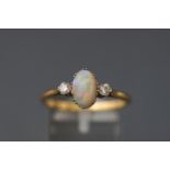 A yellow and white metal three stone ring set with an oval cabochon cut opal.