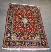A Persian style rug with central medallion surrounded by stylised flowers within three borders on a
