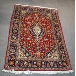 A Persian style rug with central medallion surrounded by stylised flowers within three borders on a