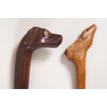 A pair of walking sticks, one carved with a dogs head, the other as a deer,