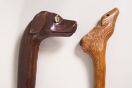 A pair of walking sticks, one carved with a dogs head, the other as a deer,