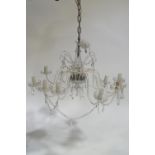 A cut glass twelve branch chandelier with luster swags and pendant drop from a central baluster