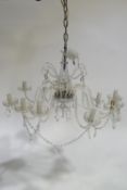 A cut glass twelve branch chandelier with luster swags and pendant drop from a central baluster