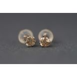 A white metal pair of single stone diamond stud earrings. Stated total weight of 0.40 carats.