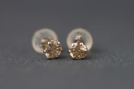 A white metal pair of single stone diamond stud earrings. Stated total weight of 0.40 carats.
