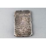 A small silver card case with profuse engraved scroll decoration to the shaped case,